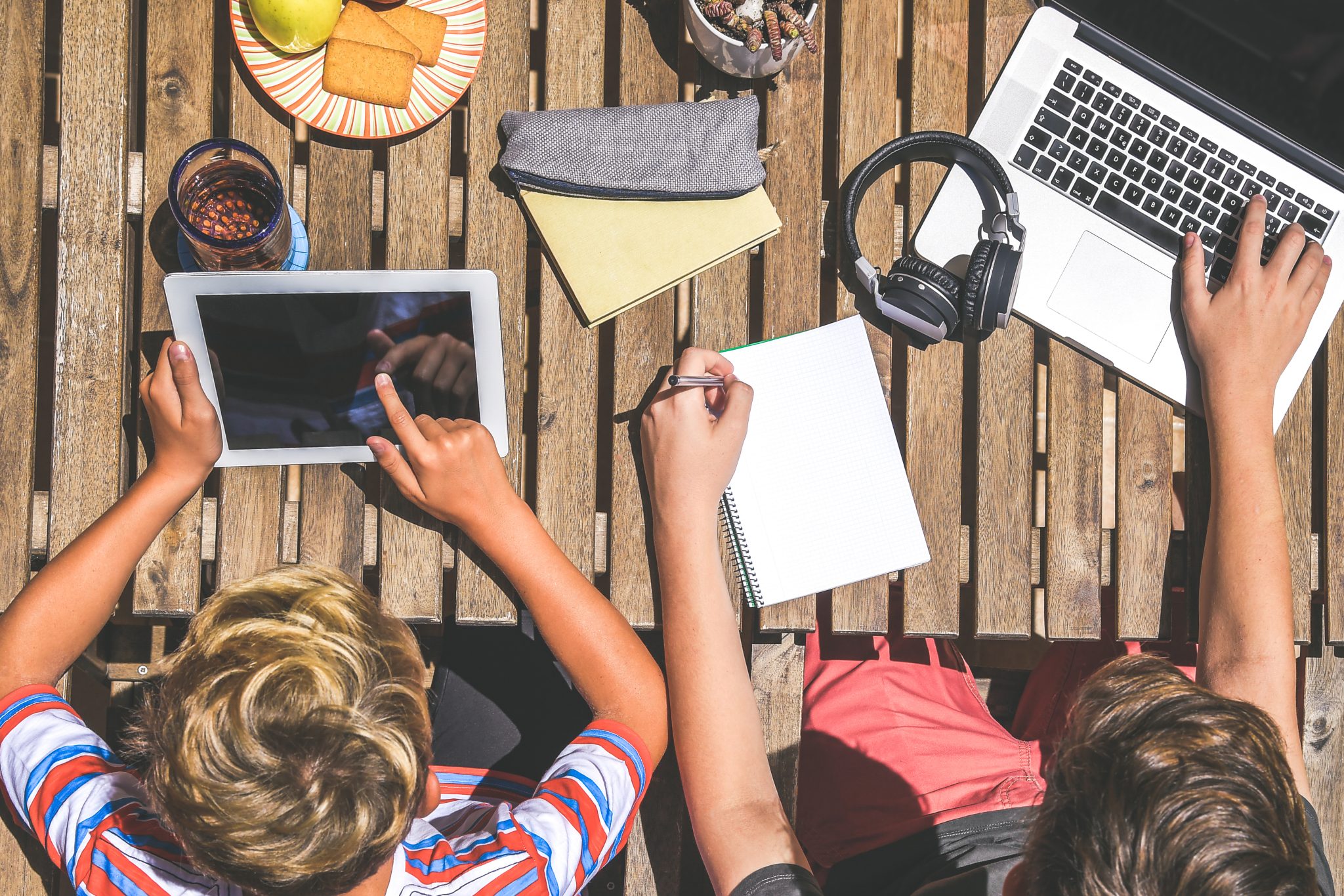 Friends having fun together playing with tech modern device. Young boys making homework together. Generation z student using laptop and tablet. Technology, youth educational and friendship concept.
